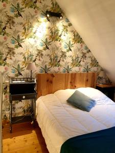 サン・ヴァ・ラ・ウグにあるGîte de la Ferme du Clos Giotの花柄の壁紙を用いたベッドルーム1室(ベッド1台付)