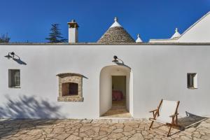 a white building with a chair on a patio at Trulli OraziO in Monopoli