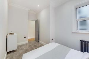 a white bedroom with a bed and a window at Brand New Luxury 2-Bed Apartment in London in London