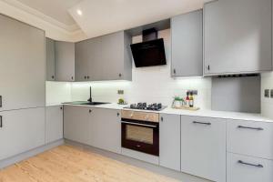 a kitchen with white cabinets and a stove top oven at Brand New Luxury 2-Bed Apartment in London in London