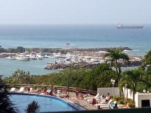 a swimming pool with a view of the water and boats at Airport BleuSuite Apartment in Catia La Mar