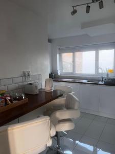 een keuken met witte kasten en een tafel en stoelen bij Home in Basildon, Essex in Basildon