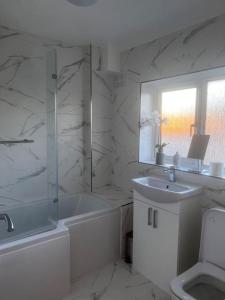 a white bathroom with a shower and a sink at Home in Basildon, Essex in Basildon