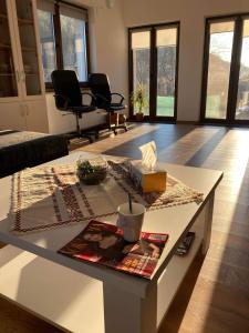 uma sala de estar com uma mesa com um livro e cadeiras em Pensiunea Nossa Panzió em Corunca