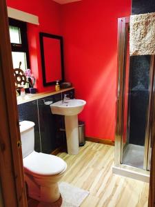 a red bathroom with a toilet and a sink at Snowberry Cottage No 2 in Onich
