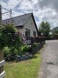 a house with a fence and flowers in front of it at Snowberry Cottage No 2 in Onich