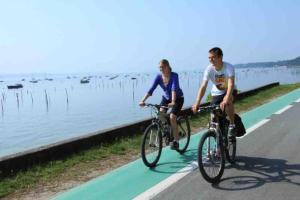 due persone che vanno in bicicletta su una pista ciclabile vicino all'acqua di Maison à Arcachon avec piscine hors-sol ad Arcachon