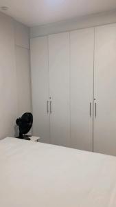 ein Schlafzimmer mit weißen Schränken und einem schwarzen Stuhl in der Unterkunft HOME SERVICE MAR & SOL in Porto De Galinhas