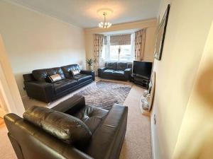 a living room with a leather couch and a television at The Old High Road in Stevenston