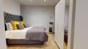 ein Schlafzimmer mit einem großen Bett mit gelben Kissen in der Unterkunft 1 Castle Yard in Coventry
