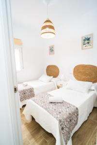 een witte kamer met 2 bedden en een tafel bij Apartamento Patio Real in Ronda