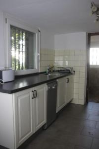 eine Küche mit weißen Schränken, einem Waschbecken und einem Fenster in der Unterkunft Vogesenblick in Offenburg