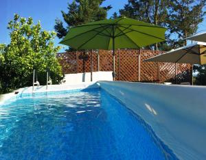 a swimming pool with a green umbrella next to it at LA CORTE DEL MULINO 1725 in San Salvatore Telesino
