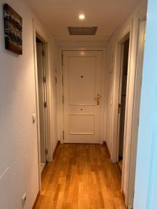um corredor vazio com uma porta branca e pisos de madeira em Adolfo Suárez Madrid apartments em Madri