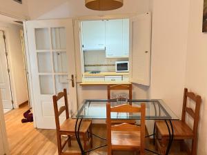 uma cozinha com uma mesa de vidro e 2 cadeiras em Adolfo Suárez Madrid apartments em Madrid