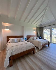 a bedroom with two beds and a large window at Victorias Villas in Villa de Leyva