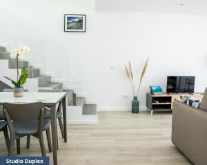 ein Wohnzimmer mit einem Tisch, Stühlen und einer Treppe in der Unterkunft TRIADE Apartamentos in Aveiro