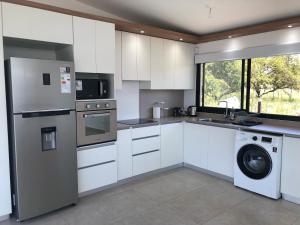 a kitchen with white cabinets and a washer and dryer at Olivos del Solar in Villa General Belgrano