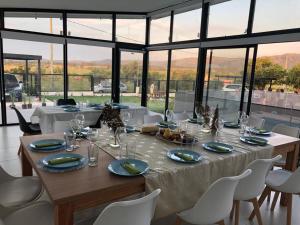 comedor con mesa, sillas y ventanas en Olivos del Solar en Villa General Belgrano