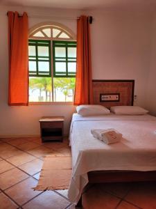 a bedroom with two beds and a large window at Pousada Villa Rosada in Santa Cruz Cabrália