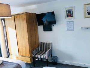1 dormitorio con silla y TV en la pared en The Players Golf Club en Bristol