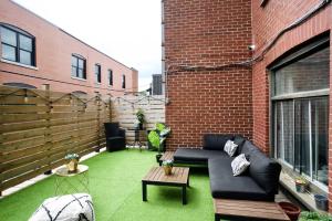 a patio with a black couch on a green lawn at M11 Upscale Comfy Studio wAC in Perfect Location in Montréal