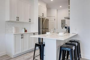 a kitchen with white cabinets and a counter with stools at M11 Upscale Spacious 1BR wKingBed AC in Heart of PlateauMile-End in Montréal