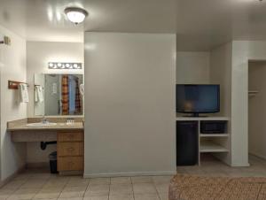 a bathroom with a sink and a tv in a room at Americas Best Value Inn Oxnard-Port Hueneme in Port Hueneme