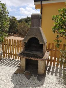 un horno de piedra sentado junto a una valla en Tana della Volpe, en Arbus