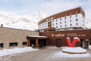 un edificio de hotel con una montaña cubierta de nieve en el fondo en Valtur Cervinia Cristallo Ski Resort en Breuil-Cervinia