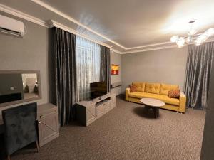 a living room with a yellow couch and a television at Rooms Hotel Semey in Semey