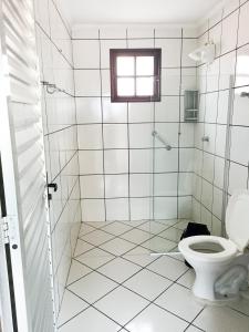 baño de azulejos blancos con aseo y ventana en Itapuã Corais Hostel e Pousada, en Salvador
