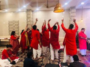 a group of people dancing in a room with their hands up at Hotel Bali Resort extension in Katra