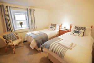 1 dormitorio con 2 camas, silla y ventana en Cliff Cottage en Gorran Haven