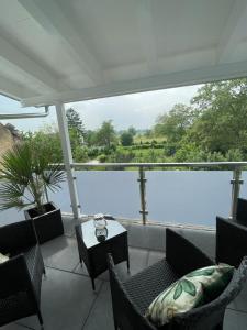 a balcony with chairs and a table with a view of the water at Ferienwohnungen im Palmengarten - 40 qm in Heitersheim