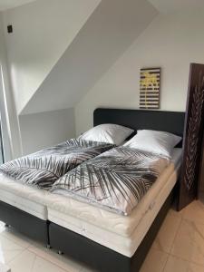a bed with a black frame and white sheets and pillows at Ferienwohnungen im Palmengarten - 40 qm in Heitersheim