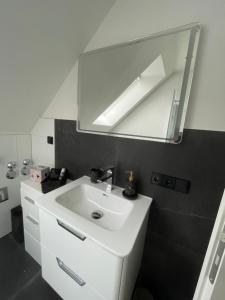 a bathroom with a white sink and a mirror at Ferienwohnungen im Palmengarten - 40 qm in Heitersheim