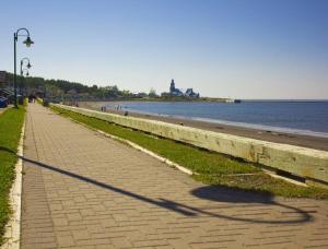 a sidewalk next to a beach with the ocean at Corail de mer app 3 à juste 2 min de la plage in Sainte-Luce-sur-Mer