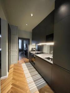 a kitchen with black cabinets and a wooden floor at New Luxury Apartment Vienna in Vienna