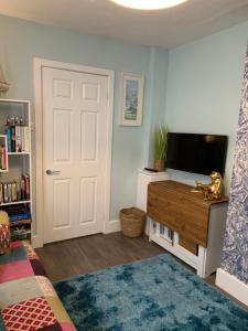 a living room with a tv and a door and a room with a rug at Ground Floor Apartment in Exmouth