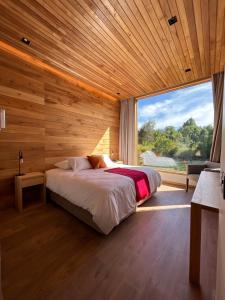 a bedroom with a bed and a large window at Mawün Lodge in Villarrica