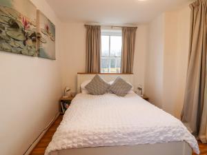 a bedroom with a white bed with a window at Lair Close Cottage in Birstwith