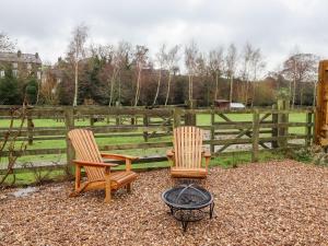 two chairs and a fire pit in front of a fence at Lair Close Cottage in Birstwith