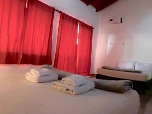 Habitación con 2 camas y cortinas rojas. en Hotel Puerto Libertad - Iguazú en Puerto Libertad