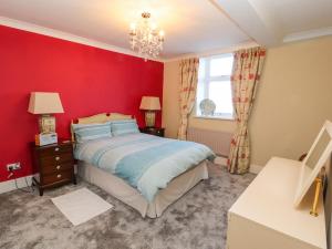 a red bedroom with a bed and a window at Greenmantle in Skinburness