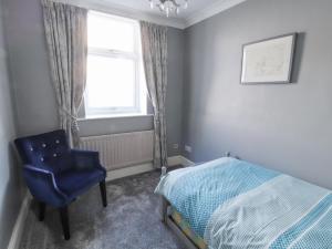 a bedroom with a bed and a blue chair and a window at Greenmantle in Skinburness