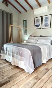 a bedroom with a large bed and a wooden floor at Suíte Ilhinha II em condomínio na Praia do Perequê in Ilhabela