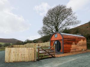 a small wooden cabin next to a wooden fence at Callow Pod in Shrewsbury