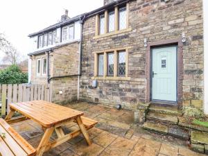 a wooden picnic table in front of a brick building at Woods Lane Cottage in Oldham