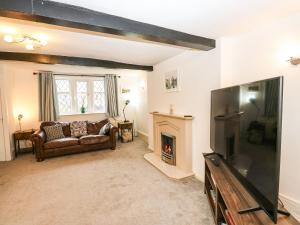 a living room with a couch and a television at Woods Lane Cottage in Oldham